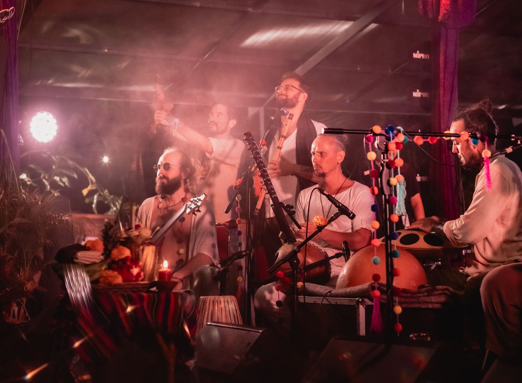 Acharya with the band in pink stage haze, kora, flute, bass and handpan
